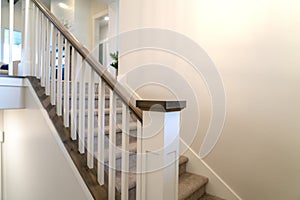 Indoor staircase of a home with white balusters brown handrail and newel