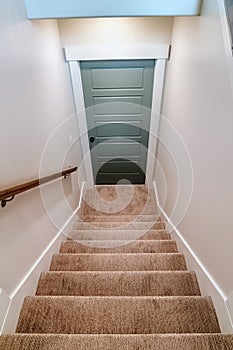 Indoor stairs of home with carpeted treads that leads down to the basement door