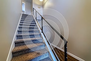 Indoor stairs of home with metal handrail and gray carpet on the treads
