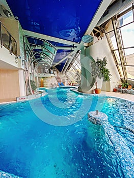 Indoor swimming pool with water slide, azure ceiling for leisure in a building