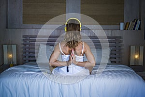 Indoors back portrait of beautiful and fit healthy woman 30s practicing yoga in bed calm and relaxed concentrated in meditation n
