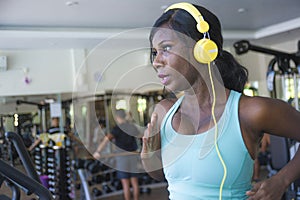 Indoors gym portrait of young attractive black afro American woman with headphones training hard all sweaty at fitness club a trea