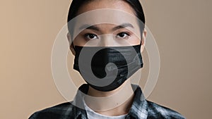 Indoors portrait close facial expression female face asian race woman ill serious girl in black protective medical mask