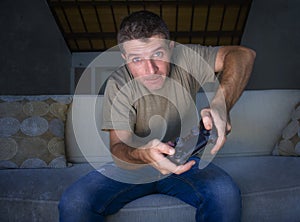 Indoors portrait of young excited and happy man at home playing videogames holding controller enjoying cheerful in video gaming