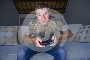 Indoors portrait of young excited and happy man at home playing videogames holding controller enjoying cheerful in video gaming