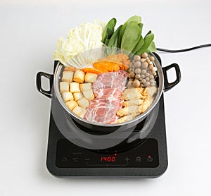 Induction cooktop with sukiyaki pot isolated on white