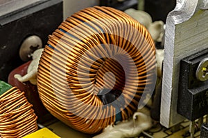 An inductor, toroidal coil on a ring with visible copper scroll, wound on a magnetic coil.