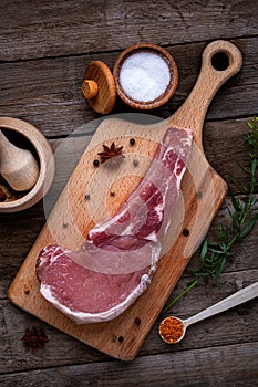 Indulge in the rustic charm of a raw piece of pork loin on a wooden board