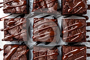 Indulgent brownies, topped with chocolate sauce, elegantly presented on white backdrop