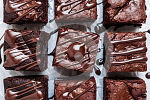 Indulgent brownies, topped with chocolate sauce, elegantly presented on white backdrop