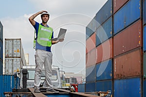 Industrail background of caucasian containers yard and cargo inspector with laptop computer on hand working at containers loading