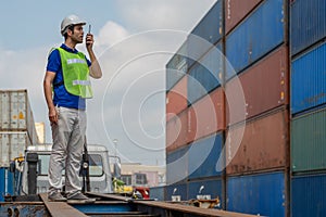 Industrail background of caucasian containers yard and cargo inspector with radio on hand working at containers loading area