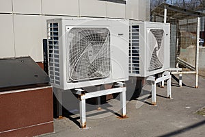 Industrial air conditioner condensers outdoor unit on the ground near the building on a hot summer day