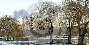 Industrial air pollution. Winter landscape with factory and trees. The concept of environmental pollution.