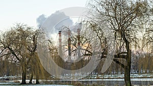 Industrial air pollution. Winter landscape with factory and trees. The concept of environmental pollution