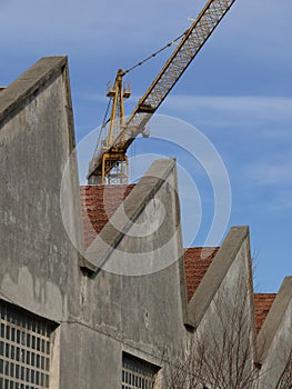 Industrial archeology buildings in the city of Busto Arsizio. Facade of ancient factory shed. Construction crane photo