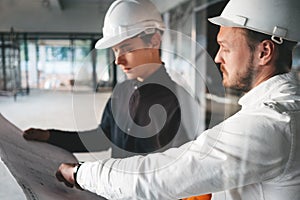 Industrial architect discussing build drawing with worker wearing safety hard hat