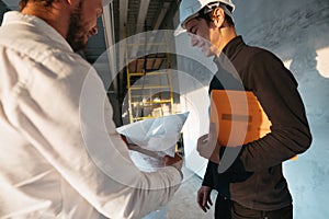 Two building engineers lookin at blueprint on construction site photo