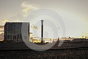 Industrial area with pipes on the background of an unfinished building. Evening urban landscape, sunset