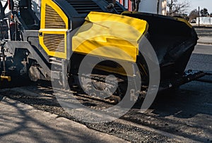 Industrial asphalt paver machine laying fresh asphalt on road construction site on the street. A Paver finisher placing