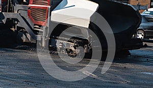 Industrial asphalt paver machine laying fresh asphalt on road construction site on the street. A Paver finisher placing