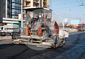 Industrial asphalt paver machine laying fresh asphalt on road construction site on the street. A Paver finisher placing