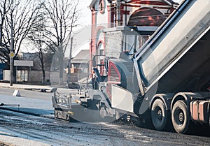 Industrial asphalt paver machine laying fresh asphalt on road construction site on the street. A Paver finisher placing