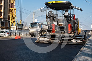 Industrial asphalt paver machine laying fresh asphalt on road construction site on the street. A Paver finisher placing