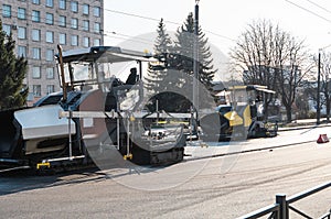 Industrial asphalt paver machine laying fresh asphalt on road construction site on the street. A Paver finisher placing