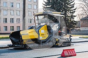 Industrial asphalt paver machine laying fresh asphalt on road construction site on the street. A Paver finisher placing