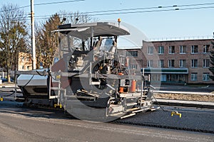 Industrial asphalt paver machine laying fresh asphalt on road construction site on the street. A Paver finisher placing