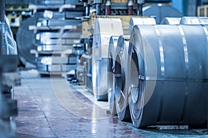 Industrial background. Big size steel coil stored inside industrial warehouse, blue toned image.