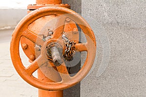 Industrial background orange big faucet on long gates with chain background of gray stone wall copy space