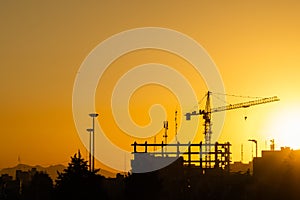 Industrial background with silhouette of construction crane at sunset.