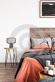 Industrial black lamp on wooden nightstand table nest to king size bed with orange and grey bedding
