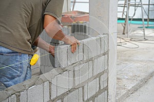 Industrial bricklayer installing brick blocks on construction site