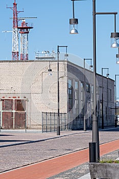 Industrial building with huge windows, doors and metal fence. Blue sky