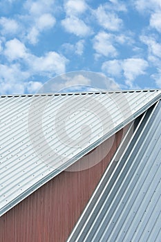 Industrial building roof sheets, grey steel rooftop pattern, bright summer clouds cloudscape, blue sky, vertical