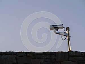 Industrial CCTV camera in solid metal enclosure. Security camera against blue sky. Outdoor surveillance equipment