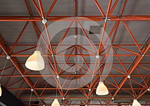 Industrial ceiling with red girders and lamps