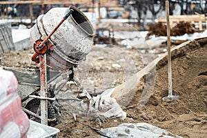 Industrial cement mixer machine at house construction site. Concrete mixer, sand and tools