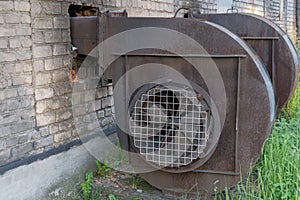 Industrial centrifugal radial exhaust fans of snail type with traces of rust, installed near building made of white bricks