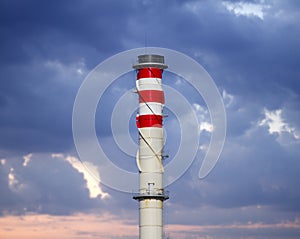 Industrial chimneys on cloudy sky at sunset