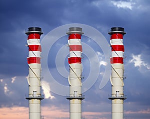 Industrial chimneys on cloudy sky at sunset