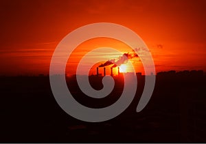 Industrial chimneys during dramatic sunset background