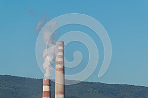 Industrial chimneys with white smoke on blue sky