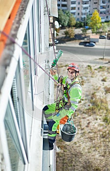 Industrial climber on building during winterization works, looking up at camera and smiling photo