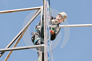 Industrial climber in helmet and overall working on height.