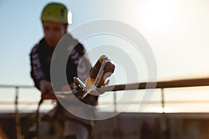 Industrial climber in a helmet pulls a rope on the roof of a building. Blurred background, background image