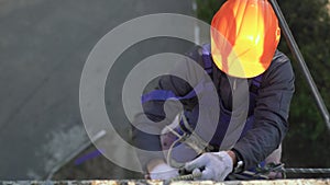 An industrial climber in a protective helmet descends from the roof of a house, construction work at a height.